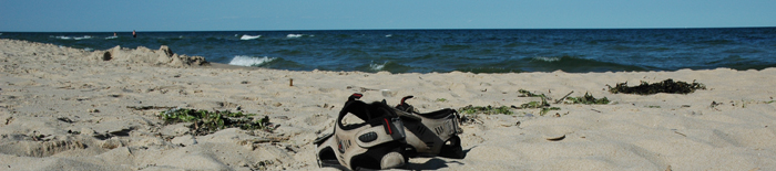 Havshorisont med en strand och ett par slitna sandaler i förgrunden.
