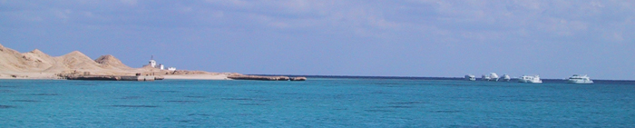 Foto med hav, rev och dykbåtar vid horisonten över Röda havet.